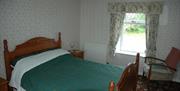A double bedroom with a chair and window.