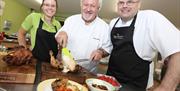 Image shows 3 people cooking chicken