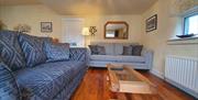 A living room sitting area with two grey sofas, a glass coffee table and a mirror.