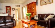 Image shows lounge area with leather sofas, wooden floor and coffee table