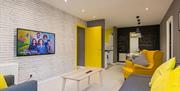 Sitting room with a TV leading to a dining area with a kitchen.