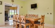 Kitchen area with table and 8 chairs.  Yellow background walls and mounted TV