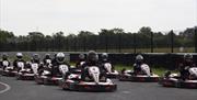 People in go-karts at the starting line of the track.