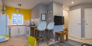 A photo of a kitchen which wraps around a wall with a tv to a living space.
