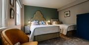 Image shows double bed and single bed in room with large chair