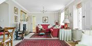 A large living room with red sofas and rugs, a fireplace and doors.