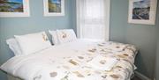 A twin bedroom with two single beds pushed together next to a window.