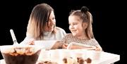 Mother and daughters making chocolates together with bowls  and trays in front of them