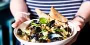 A waitress serves a bowl of Strangford Lough mussels cooked in white wine cream.