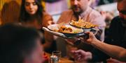 Food Tour Guests being served chicken wings and chips on Crafty Beer and Tasty Bites tour