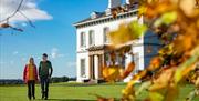 A couple walking through gardens of Ballyscullion park with the Georgian House in the background.