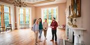 Three ladies stand with a tour guide inside the ballroom of Lissan House.