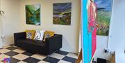 Interior of the Gallery Whitehead - black and white checked floor with black softa, white walls and framed images plus an image on an easel