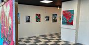 Interior of the Gallery Whitehead - black and white checked floor with white walls and framed images.