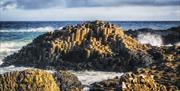 Waves crash against the stones of the Giants Causeway
