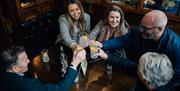 Group of 3 women and 2 men in The Crown bar doing 'cheers' action with their gin drink into the centre of the table