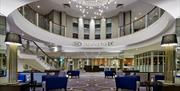 Photo of the lobby in the Crowne Plaza Belfast hotel. Modern lobby with chairs, sofas and coffee tables. View of the first floor rotunda.