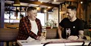 Two males seated at table having a good time at Hagen's Bar