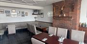 Table set up for group dining in Halfway House Hotel with brick fireplace in background and historic pictures on the walls.