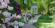 Image shows flowers in bloom at gardens of hillsborough castle with two children and an adult walking along