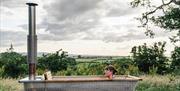 A lady reclines in the hot tub with views of the countryside in the backdrop