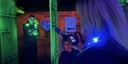 A Man and a Woman pointing Laser Tag Phasers at Each Other.
