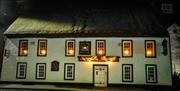 Night time exterior of the Thatch Inn Bar & Restaurant - white building with thatched roof and lights on in the upper windows