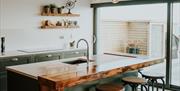 Luxury, bespoke kitchen area with a breakfast bar and large sliding doors onto a patio area.