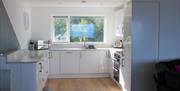 Kitchen with a sink, microwave, toaster and a large window viewing the back garden.