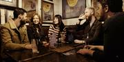 group of people at a table inside the bar chatting and enjoying drinks.