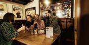 group of people at a table inside the bar chatting and enjoying drinks.