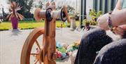 Christine using the spinning wheel outside of the Kiri Cottage Crafts workshop