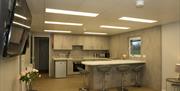 Open plan kitchen and living area with island, 4 bar stools and sofa and TV