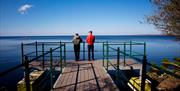 Two people stand on a lookout point over Lough Neagh