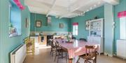 Image shows country kitchen with large dining table and chairs, dresser and all mod cons