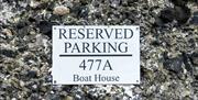 A sign for a reserved parking space for the boathouse.