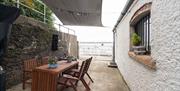 Covered outdoor eating area with garden furniture to seat four and sea views.