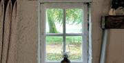 a traditional oil lamp sits on the windowsill, with a tree situated outside the window