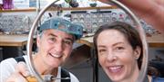 Goldsmith Ruth & lady looking through sterling silver bangle in workshop after finishing jewellery making workshop.