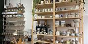 Tall shelf display with hand-made pottery including mugs, plates, bowls and more