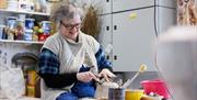 Patricia works at moulding handle on to ceramic pot in her workshop