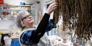 Patricia reaches for dried grass in her workshop