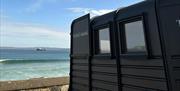 Side view of horsebox sauna, with views of the sea and blue sky in the background