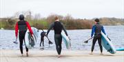 image of 3 males heading towards the lake carrying SUP paddle boards