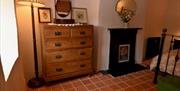A chest of drawers with a mirror and a fireplace in a bedroom.