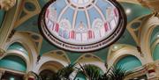 Interior of decorative ceiling dome with palm trees underneath.