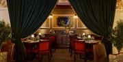 interior of the Red Sail Room dining area at Portrush Adelphi. Large velvet curtains drape either side of a snug alcove where there are various dining