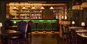 interior of the bar at the Red Sails dining area at Portrush Adelphi. There are dining tables and chairs, as well as bar stools along the main serving
