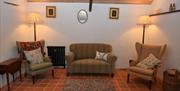 A tiled cottage lounge area with two chairs and a sofa.