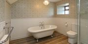 Bathroom featuring rolltop stand along bath